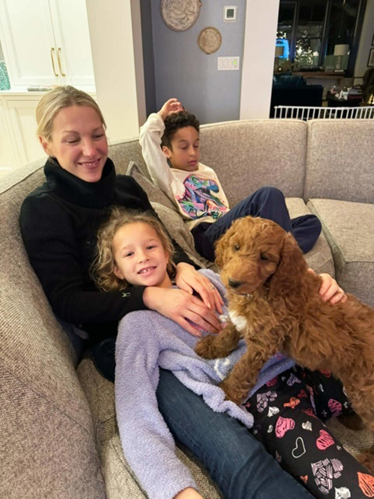 Craig Melvin's new dog makes himself comfortable on the couch next to his family.  (Courtesy of Craig Melvin)