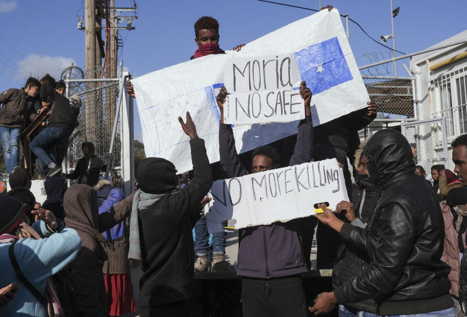 Refugees and migrants hold placards as they demonstate outside Moria camp, following the stabbing death of an 20-year-old man from Yemen in the Greek island of Lesbos, Friday, Jan, 17, 2020. Authorities arrested a 27-year-old Afghan migrant in connection with the incident. Overcrowding at Moria has steadily worsened over the past year as the number of arrivals of migrants and refugees using clandestine routes from Turkey to the Greek islands remains high _ and totaled nearly 60,000 in 2019. (AP Photo/Aggelos Barai)