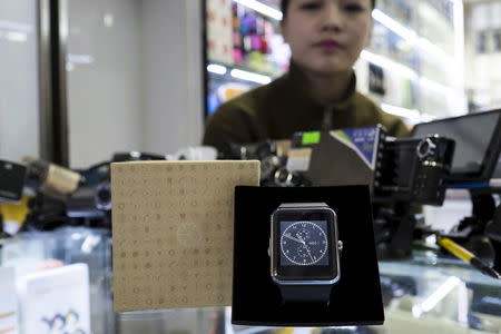 A salesman looks on as an Apple Watch look-alike device, made by a Chinese manufacturer, is displayed at a mall selling electronic products in China's southern city of Shenzhen, April 8, 2015. REUTERS/Tyrone Siu