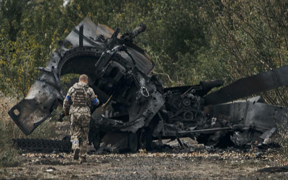 A Ukrainian soldier passes by a Russian tank damaged in a battle in a newly liberated territory on the road to Balakleya in the Kharkiv region of Ukraine on Sept. 11, 2022. (AP Photo)