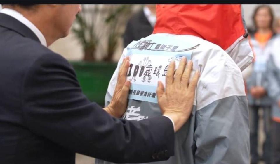 副總統賴清德在百歲不老騎士郭深森衣服背面貼上「我100歲，環島中」大貼紙。（總統府）