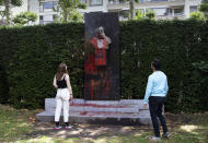 FILE - In this Friday, June 19, 2020 file photo, a couple stop to look at a bust of Belgium's King Leopold II, which has been damaged by red paint, graffiti and cement, at a park in Ghent, Belgium. Protests sweeping the world after George Floyd's death in the U.S. have added fuel to a movement to confront Europe's role in the slave trade and its colonial past. Leopold II is increasingly seen as a stain on the nation where he reigned from 1865 to 1909 with some demonstrators wanting him removed from public view. (AP Photo/Virginia Mayo, File)