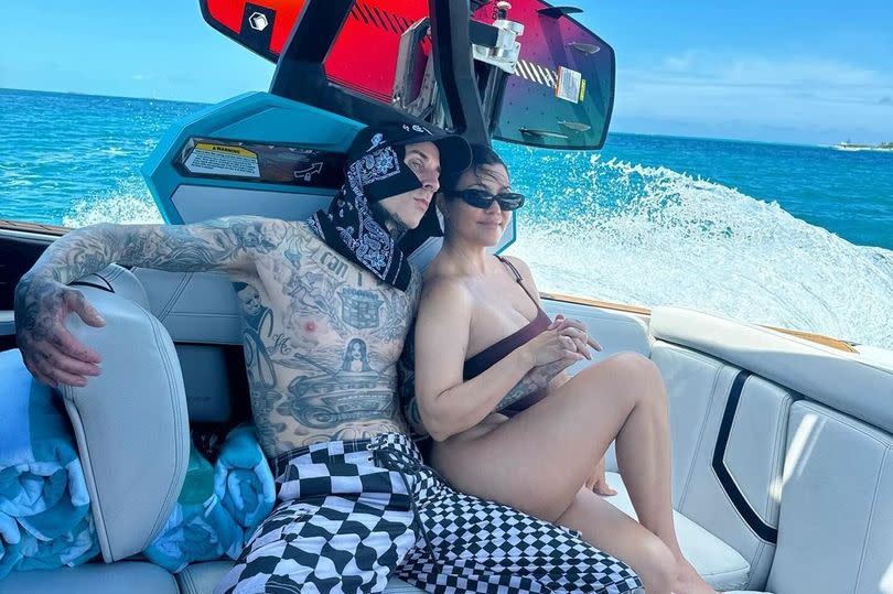 Travis Barker and wife Kourtney Kardashian posing on a yacht