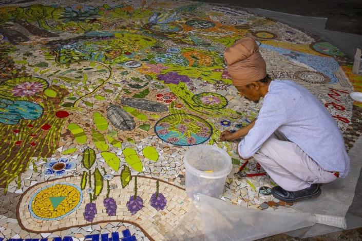 A man works on a floor mosaic.