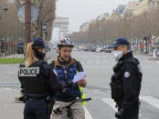 Police officers wearing protective masks check the paper of a cyclist at a control point at the Champs Elysees avenue in Paris, Tuesday, March 17, 2020. France is imposing nationwide restrictions on how far from their homes people can go and for what purpose as part of the country's strategy to stop the spread of the new coronavirus. For most people, the new coronavirus causes only mild or moderate symptoms, such as fever and cough. For some, especially older adults and people with existing health problems, it can cause more severe illness, including pneumonia. (AP Photo/Michel Euler)