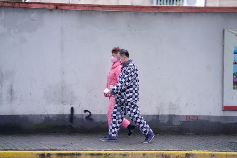 Residentes con mascarillas y pijamas son vistos en una calle de Shangai, China, mientras el país es golpeado por un brote del novedoso coronavirus, 14 de febrero de 2020