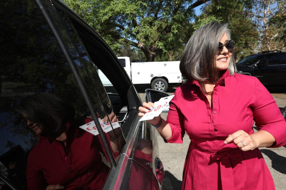 A woman stands next to a vehicle.