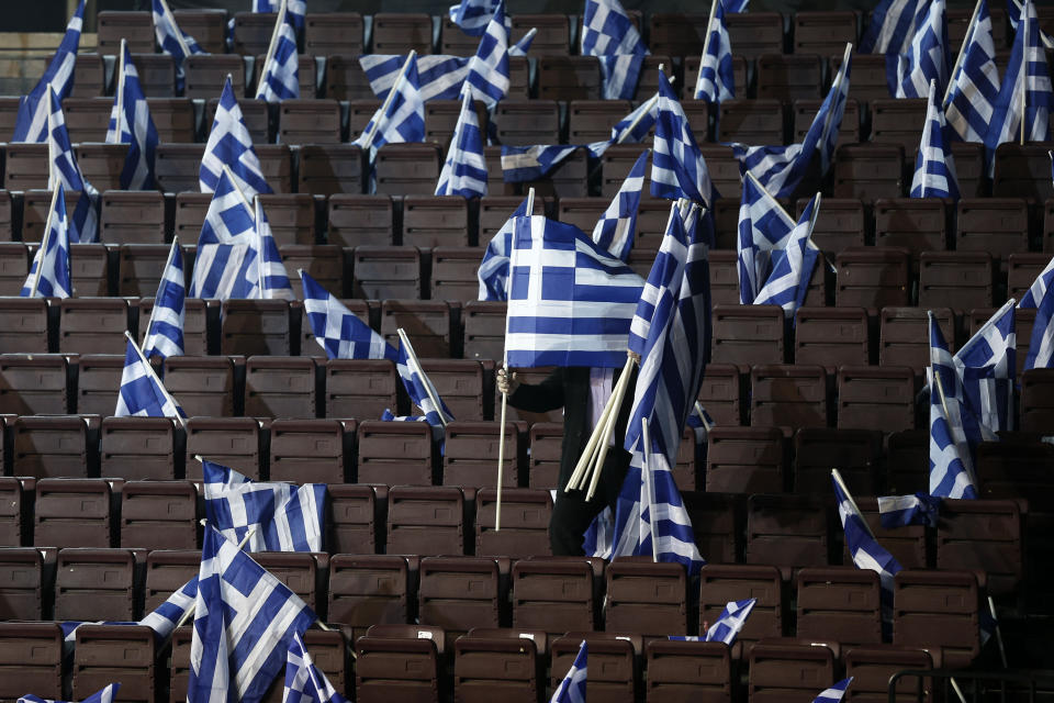 A man places Greek flags on seats for New Democracy party supporters ahead of Prime Minister's Antonis Samaras pre-election speech at the Taekwondo Indoor Stadium in southern Athens on Friday, Jan. 23, 2015. (AP Photo/Petros Giannakouris)