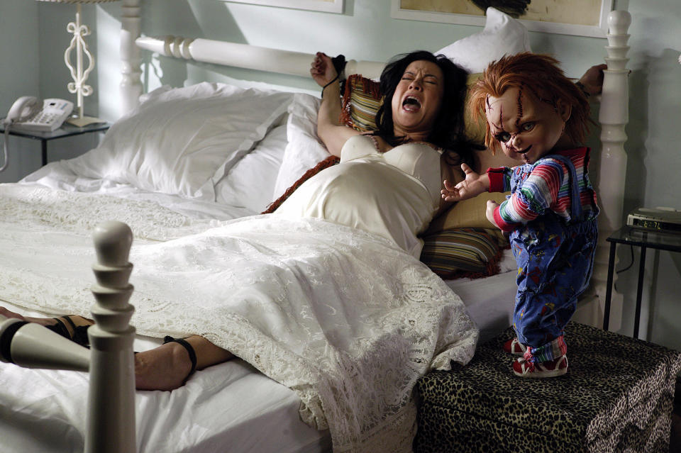 Chucky next to a woman screaming and tied to a bed in "Seed of Chucky"