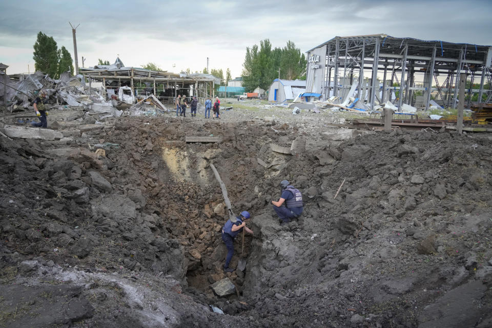 Police members inspect a crater caused by a Russian rocket attack in Pokrovsk, Donetsk region, Ukraine, Wednesday, June 15, 2022. (AP Photo/Efrem Lukatsky)
