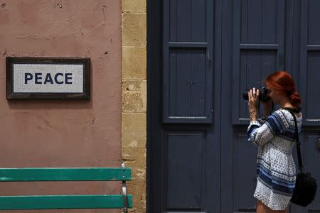 A tourist takes pictures of a peace sign near the UN-controlled buffer zone in Nicosia, Cyprus July 22, 2016. REUTERS/Yiannis Kourtoglou