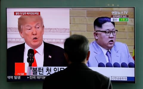 Donald Trump and Kim Jong-un appear on a TV screen at Seoul Railway Station - Credit: AP