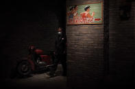 A man wearing a face mask to help curb the spread of the coronavirus walks through an old Beijing's hutong alley inside a shopping mall in Beijing, Monday, Jan. 18, 2021. A Chinese province grappling with a spike in coronavirus cases is reinstating tight restrictions on weddings, funerals and other family gatherings, threatening violators with criminal charges. (AP Photo/Andy Wong)