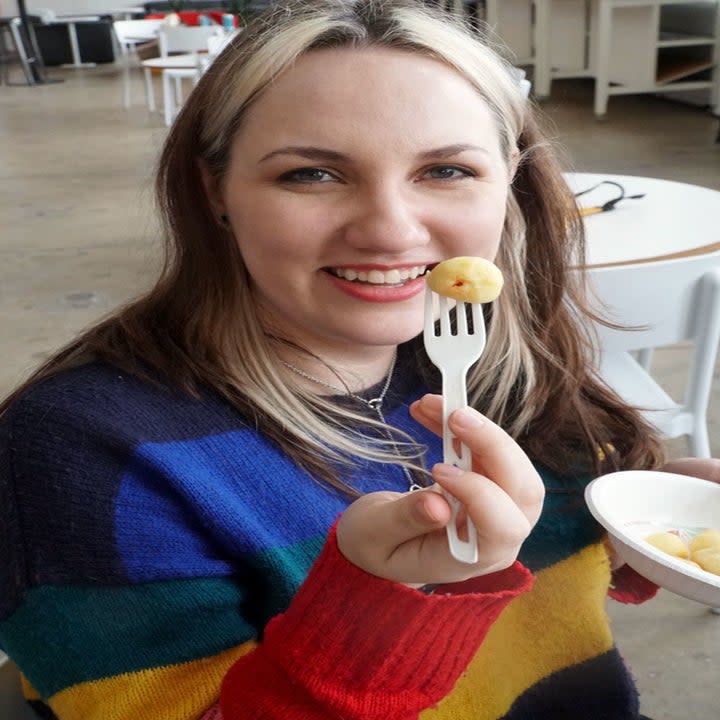 A woman holding a piece of gnocchi on a fork