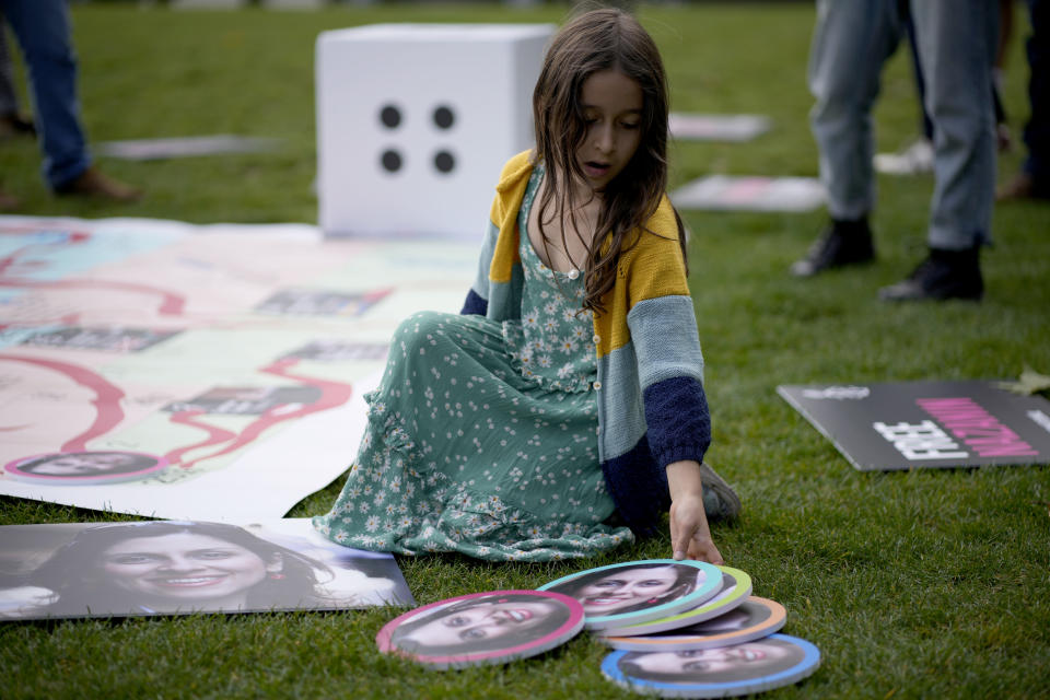 Gabriella, the seven year old daughter of imprisoned British-Iranian Nazanin Zaghari-Ratcliffe joins in a game with counters with photographs of her mother on a giant snakes and ladders board in Parliament Square, London, to show the "ups and downs" of Zaghari-Ratcliffe's case to mark the 2,000 days she has been detained in Iran, Thursday, Sept. 23, 2021. Zaghari-Ratcliffe was originally sentenced to five years in prison after being convicted of plotting the overthrow of Iran's government, a charge that she, her supporters and rights groups deny. While employed at the Thomson Reuters Foundation, the charitable arm of the news agency, she was taken into custody at the Tehran airport in April 2016 as she was returning home to Britain after visiting family. (AP Photo/Matt Dunham)