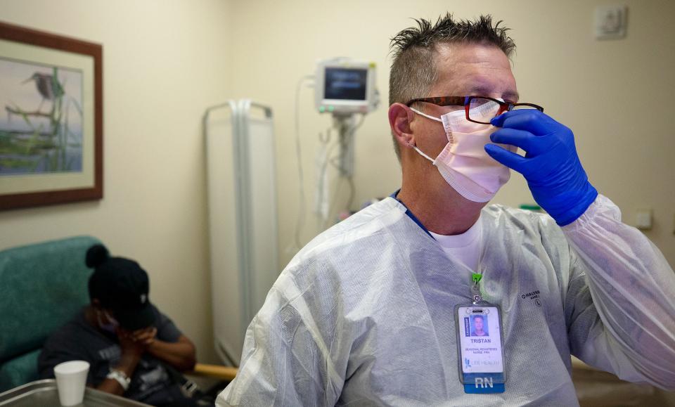 Emergency room nurse Tristan Manbevers checks in a woman complaining of COVID-19 symptoms at Gulf Coast Medical Center in Fort Myers, Fla.