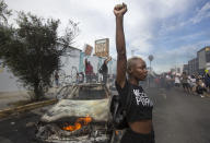 A protester poses for photos next to a burning police vehicle in Los Angeles, Saturday, May 30, 2020, during a demonstration over the death of George Floyd. a black man who was killed in police custody in Minneapolis on May 25. (AP Photo/Ringo H.W. Chiu)