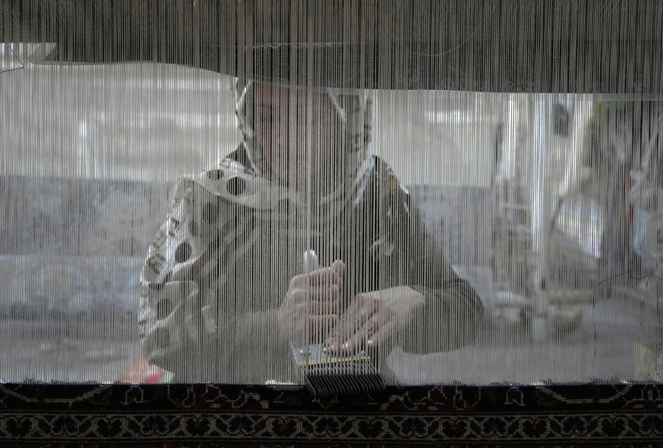 An Iranian woman weaves a carpet at a workshop in the city of Kashan, about 152 miles (245 km) south of the capital Tehran, Iran, Tuesday, April 30, 2024. (AP Photo/Vahid Salemi)