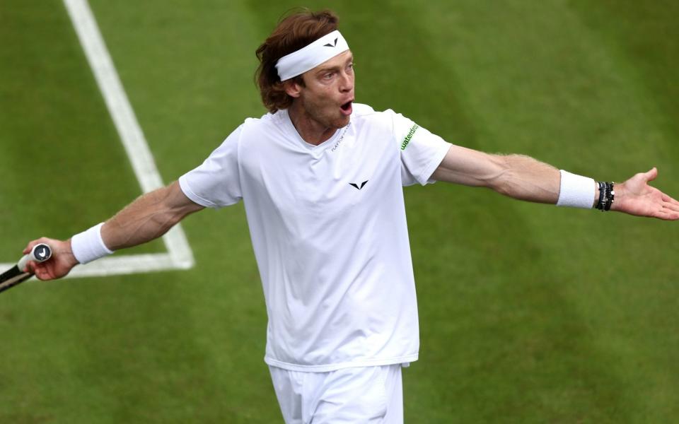 Andrey Rublev shouts with his arms wide open looking towards the stands