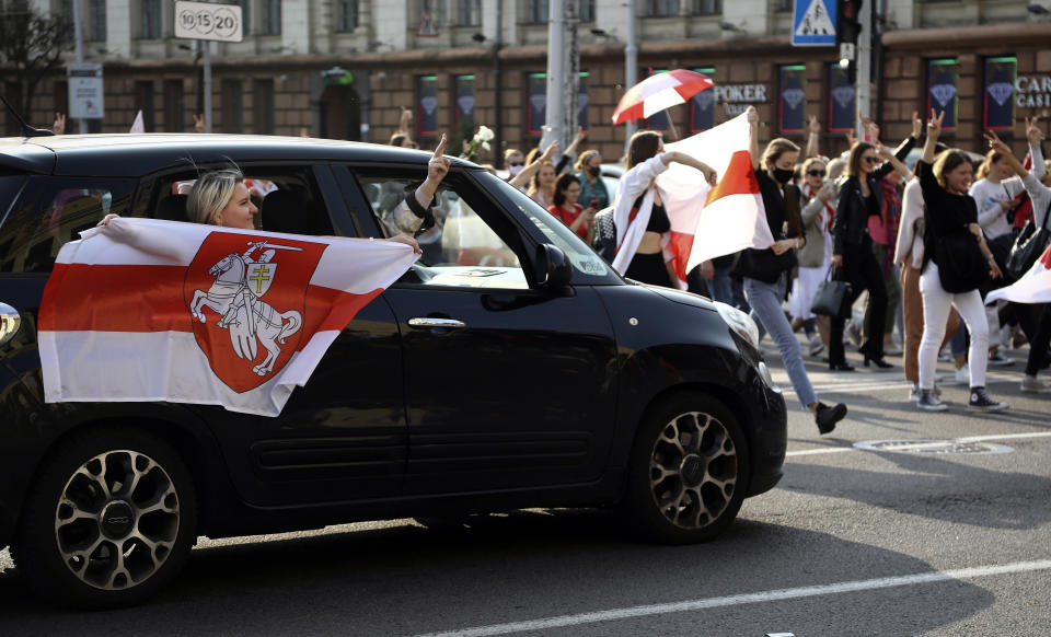 A woman waves an old Belarusian national flag from a window of a car during an opposition rally to protest the official presidential election results in Minsk, Belarus, Saturday, Sept. 12, 2020. Daily protests calling for the authoritarian president's resignation are now in their second month and opposition determination appears strong despite the detention of protest leaders. (Tut.by via AP)