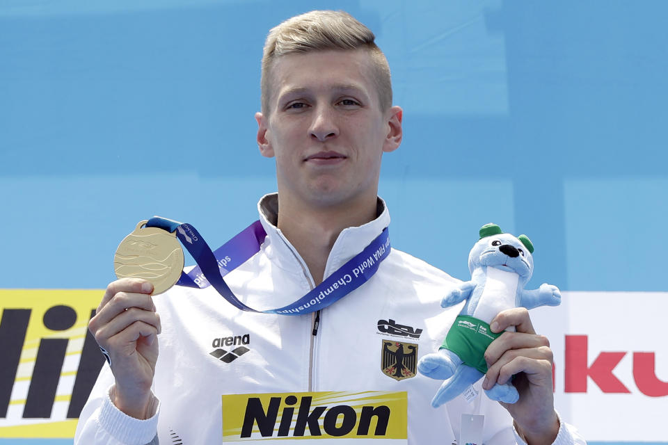 Gold medalist Florian Wellbrock of Germany stands with his medal after the men's 10km open water swim at the World Swimming Championships in Yeosu, South Korea, Tuesday, July 16, 2019. (AP Photo/Mark Schiefelbein)