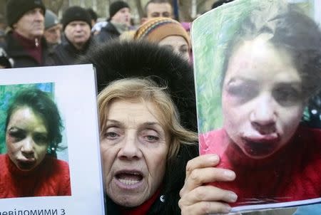 A protester holds pictures of journalist Tetyana Chornovil, who was beaten and left in a ditch just hours after publishing an article on the assets of top government officials, during a protest rally in front of the Ukrainian Ministry of Internal Affairs in Kiev December 26, 2013. REUTERS/Gleb Garanich/Files