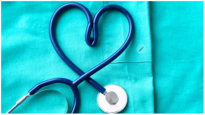 A stethoscope shaping a heart and a clipboard on a medical uniform, closeup. . AdobeStock