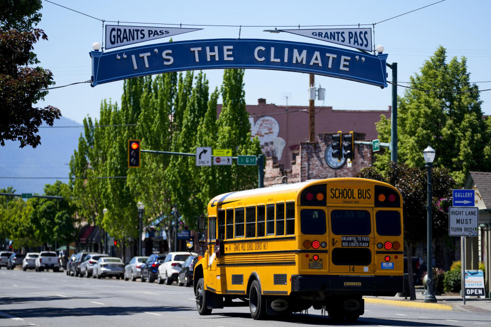 A Grants Pass School District 7 school bus drives under a city slogan sign, Thursday, May 18, 2023, in Grants Pass, Ore. (AP Photo/Lindsey Wasson)