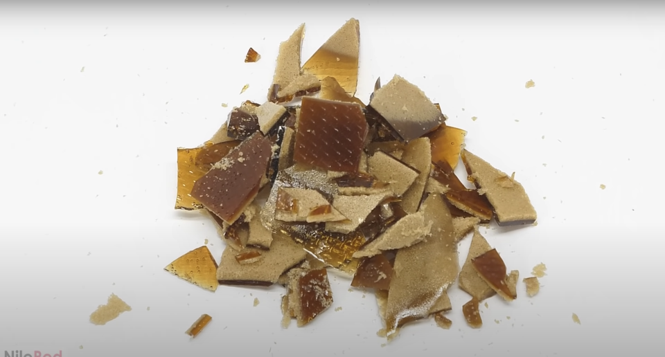 Creamy brown chips of sugar in a small pile against a white backdrop.