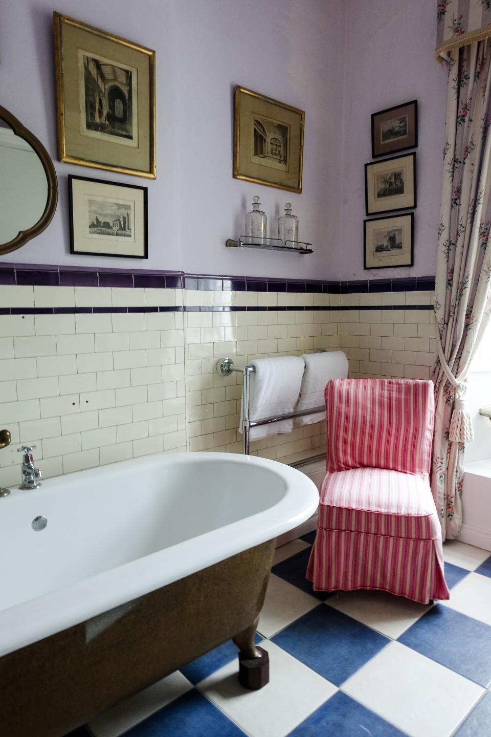 This lavender bathroom features a gallery wall and a claw-footed tub, all of which preserve the castle's ample Irish charm.