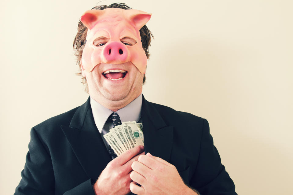 a businessman with a pig mask on holding cash money.