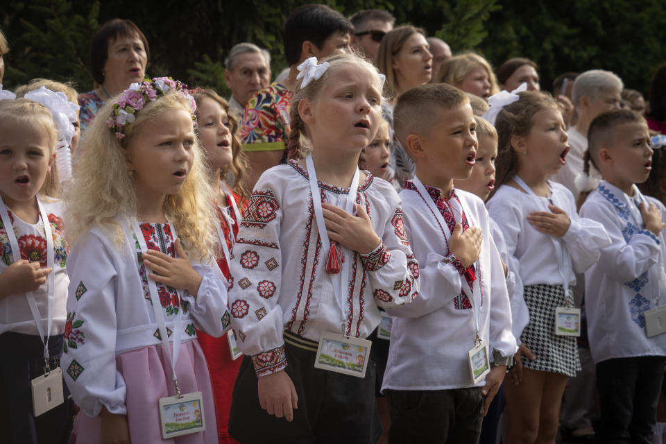 Escolares cantan el himno nacional de Ucrania en la ceremonia de regreso a clases en Bucha, Ucrania, 1 de setiembre de 2023. El inicio del año escolar se festeja como Día del Conocimiento. (AP Foto/Efrem Lukatsky)