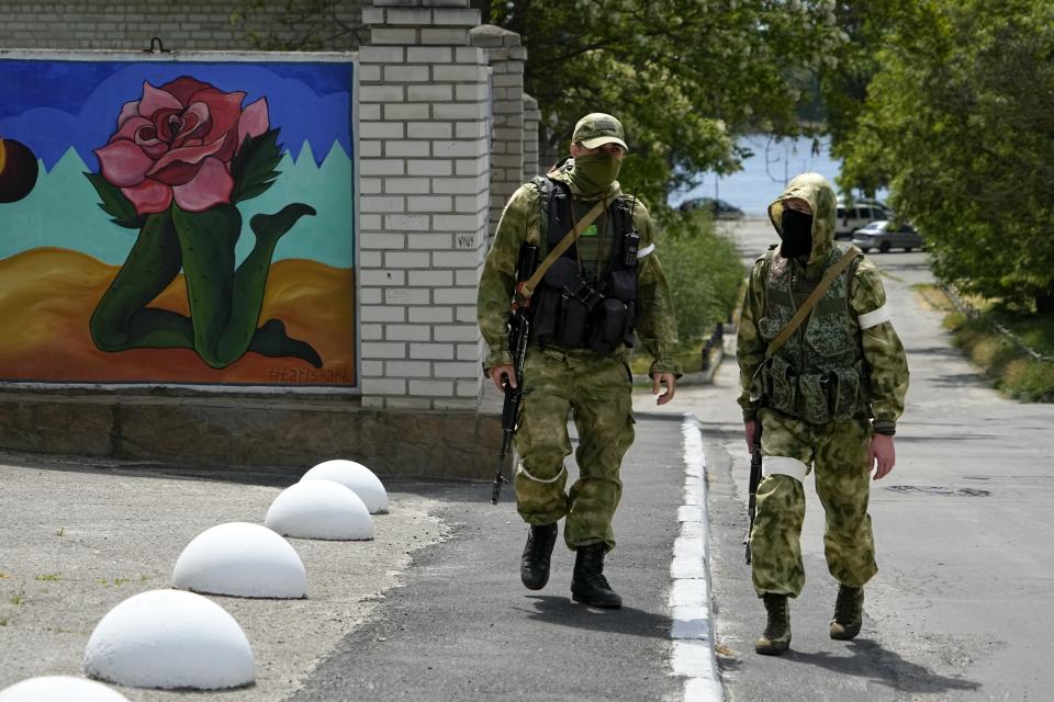 FILE - Two Russian soldiers patrol an administrative area at the Khersonvodokanal (water channel) in Kherson, Kherson region, south Ukraine, on May 20, 2022. In the southern city of Kherson, one of the first seized by Russia and a key target of an unfolding Ukrainian counteroffensive, the Ukrainian mayor tried to stand his ground. As Russians seized parts of eastern and southern Ukraine in the 8-month-old war, mayors, civilian administrators and others, including nuclear power plant workers, say they have been abducted, threatened or beaten to force their cooperation. (AP Photo, File)