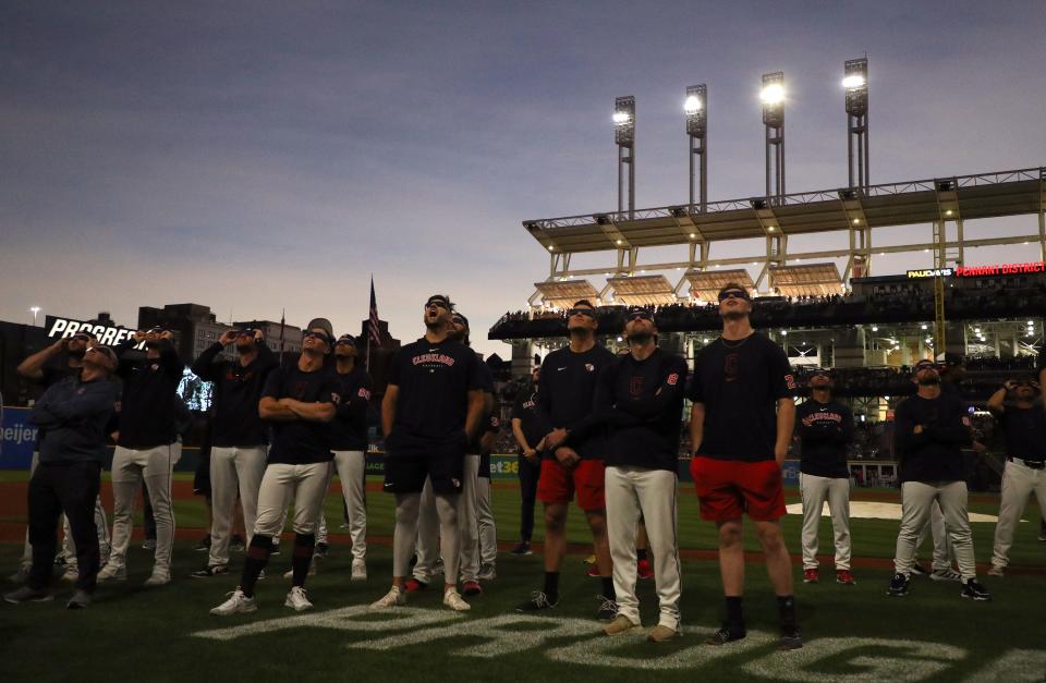 The Cleveland Guardians look up at the total solar eclipse before their home opener against the Chicago White Sox at Progressive Field on April 8, 2024 in Cleveland, Ohio.