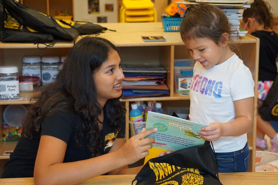 BelieveNBooks Founder Natasha Agarwal helps Guadalupe Center student Myla Martinez review books provided through the nonprofit’s new PageTurner initiative.