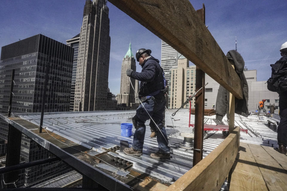 Construction workers lay down roofing on a high rise at 160 Water Street in Manhattan's financial district, for the building's conversion to residential apartments, Tuesday, April 11, 2023, in New York. (AP Photo/Bebeto Matthews)