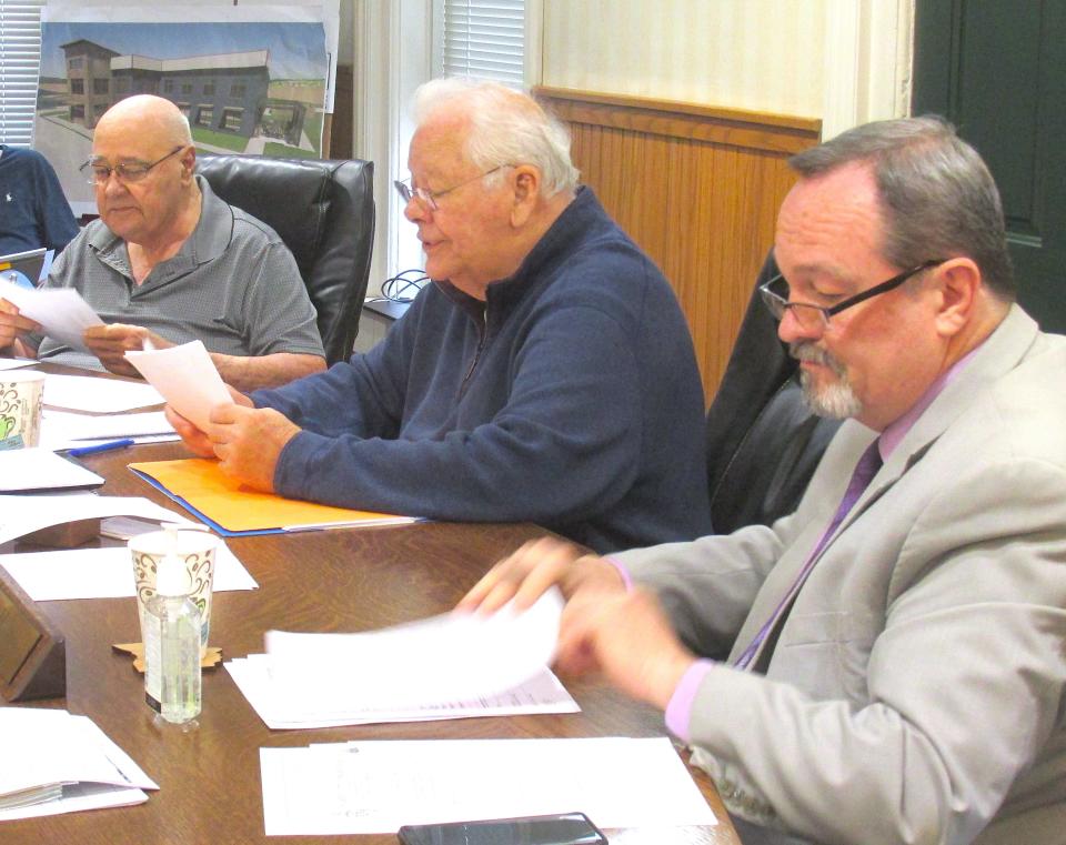 Chairman of the Holmes County Board of Commissioners, Joe Miller, center, reads the resolution to enter into an agreement with Troyer Manufacturing on a sewer expansion project, as Commissioners Ray Eyler, left, and Dave Hall look on.
