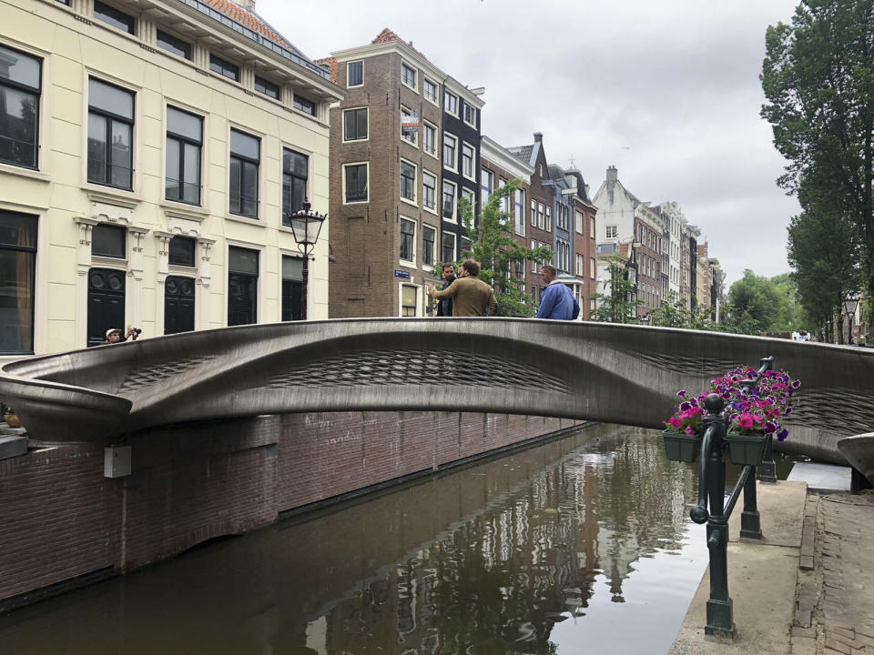 A steel 3D-printed pedestrian bridge spans a canal in the heart of the red light district in Amsterdam, Netherlands, Thursday, July 15, 2021. The distinctive flowing lines of the 12-meter (40-foot) bridge were created using a 3D printing technique called wire and arc additive manufacturing that combines robotics with welding. (AP Photo/Aleksandar Furtula)