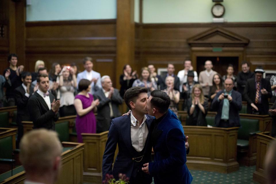 Sean Adl-Tabatabai, left, and Sinclair Treadway kiss each other as they are announced officially married during a wedding ceremony in the Council Chamber at Camden Town Hall in London, minutes into Saturday, March 29, 2014. Gay couples in Britain waited decades for the right to get married. When the opportunity came, some had just days to plan the biggest moment of their lives. Adl-Tabatabai, a 32-year-old TV producer from London, and Treadway, a 20-year-old student originally from Los Angeles, registered their intent to marry on March 13, the first day gay couples could sign up for wedding ceremonies under Britain's new law. Eager to be part of history, the two men picked the earliest possible moment - just after midnight Friday, when the act legalizing same-sex marriage takes effect. (AP Photo/Matt Dunham)