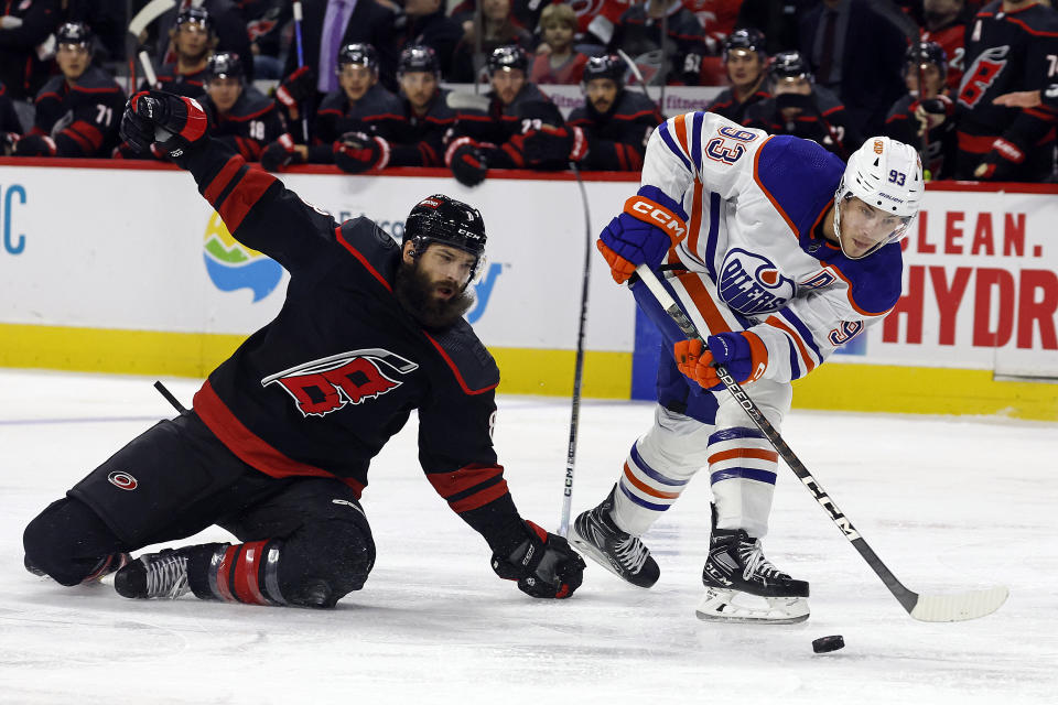 Edmonton Oilers' Ryan Nugent-Hopkins (93) skates away from Carolina Hurricanes' Brent Burns (8) with the puck during the first period of an NHL hockey game in Raleigh, N.C., Wednesday, Nov. 22, 2023. (AP Photo/Karl B DeBlaker)