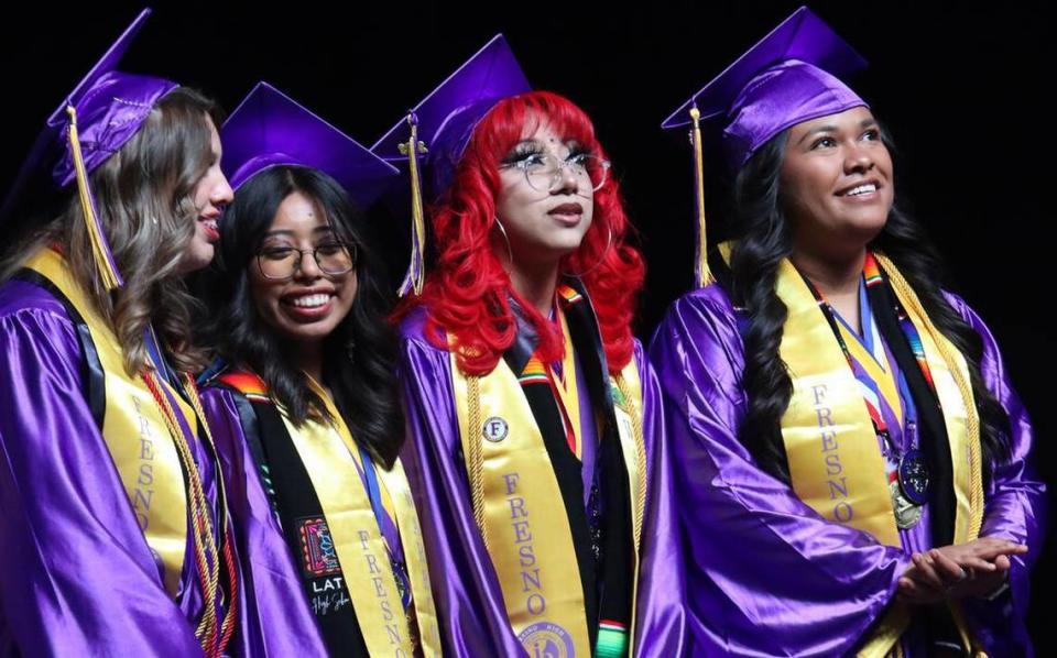 Giselle Brenda Mendoza Rendón (with red hair) looks at the video along with fellow valedictorians during the Fresno High graduation ceremony held at the Save Mart Center on June 5, 2023.