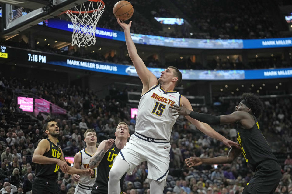 Denver Nuggets center Nikola Jokic (15) goes to the basket as Utah Jazz forward Taylor Hendricks, right, defends during the first half of an NBA basketball game Tuesday, April 9, 2024, in Salt Lake City. (AP Photo/Rick Bowmer)