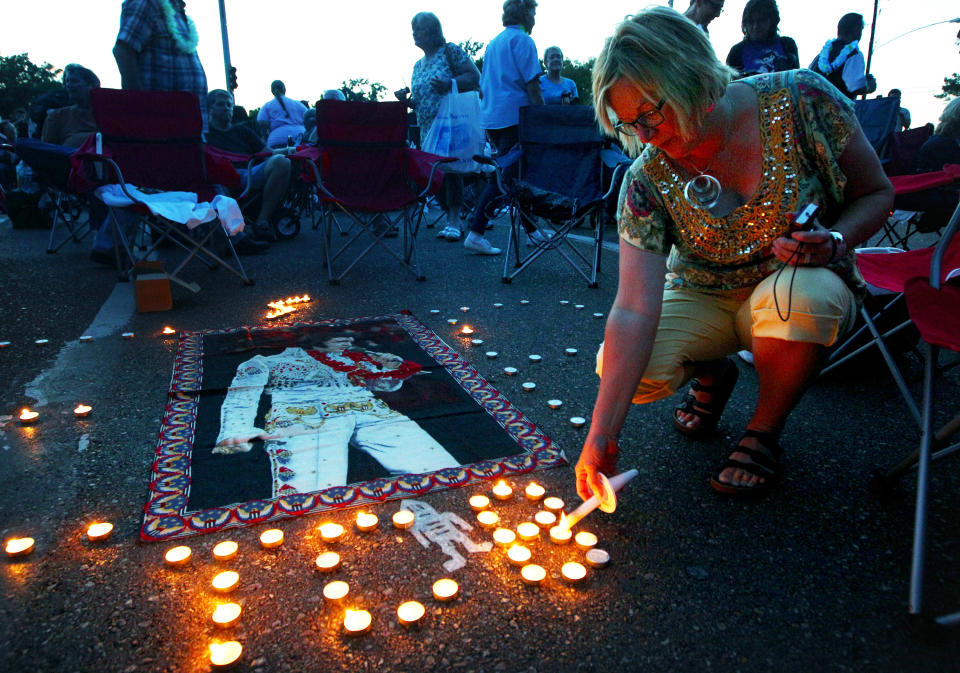 Elvis Presley fan Jill Gibson lights candles outside Graceland, Presley's home, before the annual candlelight vigil on Thursday, Aug. 15, 2013, in Memphis, Tenn. Presley fans from around the world made their annual pilgrimage to Graceland to pay their respects to the rock n' roll icon with a solemn candlelight vigil on the 36th anniversary of his death. (AP Photo/The Commercial Appeal, Nikki Boertman)