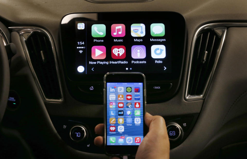 An iPhone is connected to a 2016 Chevrolet Malibu equipped with Apple CarPlay apps, displayed on the car's MyLink screen, top, during a demonstration in Detroit, Tuesday, May 26, 2015. Starting with Chevrolet this summer, many General Motors models will offer Apple’s CarPlay and Google’s Android Auto systems that link smart phones with in-car screens and electronics. (AP Photo/Paul Sancya)