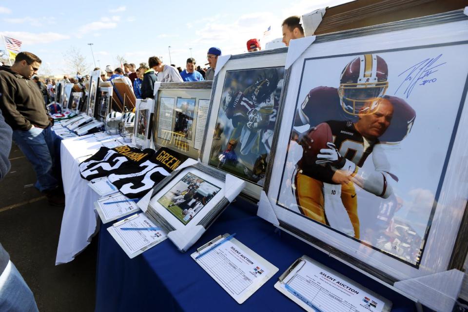 Fans look at sports memorabilia available in a silent auction held to raise money for people suffering the affects of Superstorm Sandy and cystic fibrosis before an NFL football game between the New York Giants and the Pittsburgh Steelers, Sunday, Nov. 4, 2012, in East Rutherford, N.J. (AP Photo/Julio Cortez)