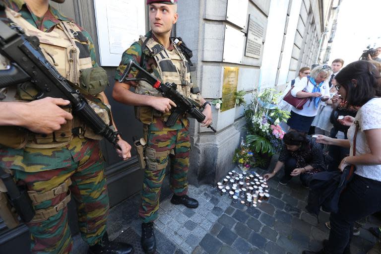 People lay down candles as soldiers stand guard at the entrance of the Jewish museum in Brussels, on May 24, 2015