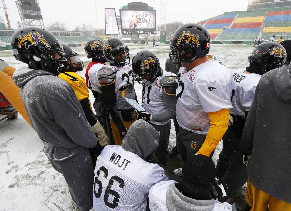 Players from the Hamilton Tiger-Cats try and warm up in the extreme cold during the team practice in Regina, Saskatchewan, November 20, 2013. The Saskatchewan Roughriders will play the Hamilton Tiger-Cats in the CFL's 101st Grey Cup in Regina November 24. REUTERS/Todd Korol (CANADA - Tags: SPORT FOOTBALL)