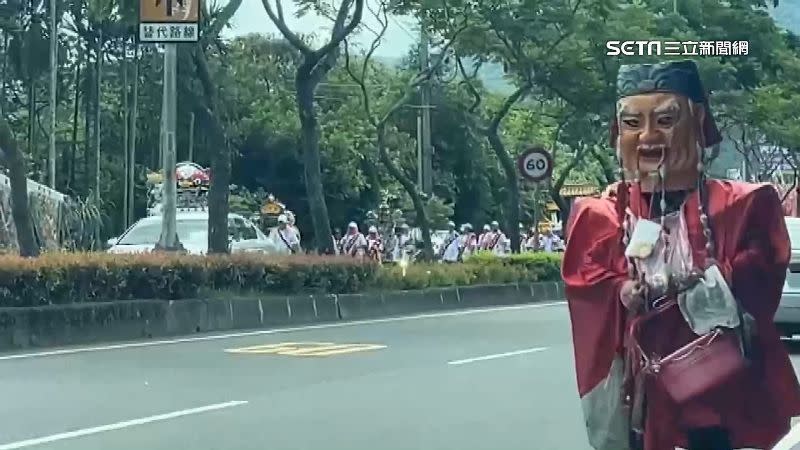 一名男子穿著破舊的土地公服飾向路旁駕駛「討紅包」。