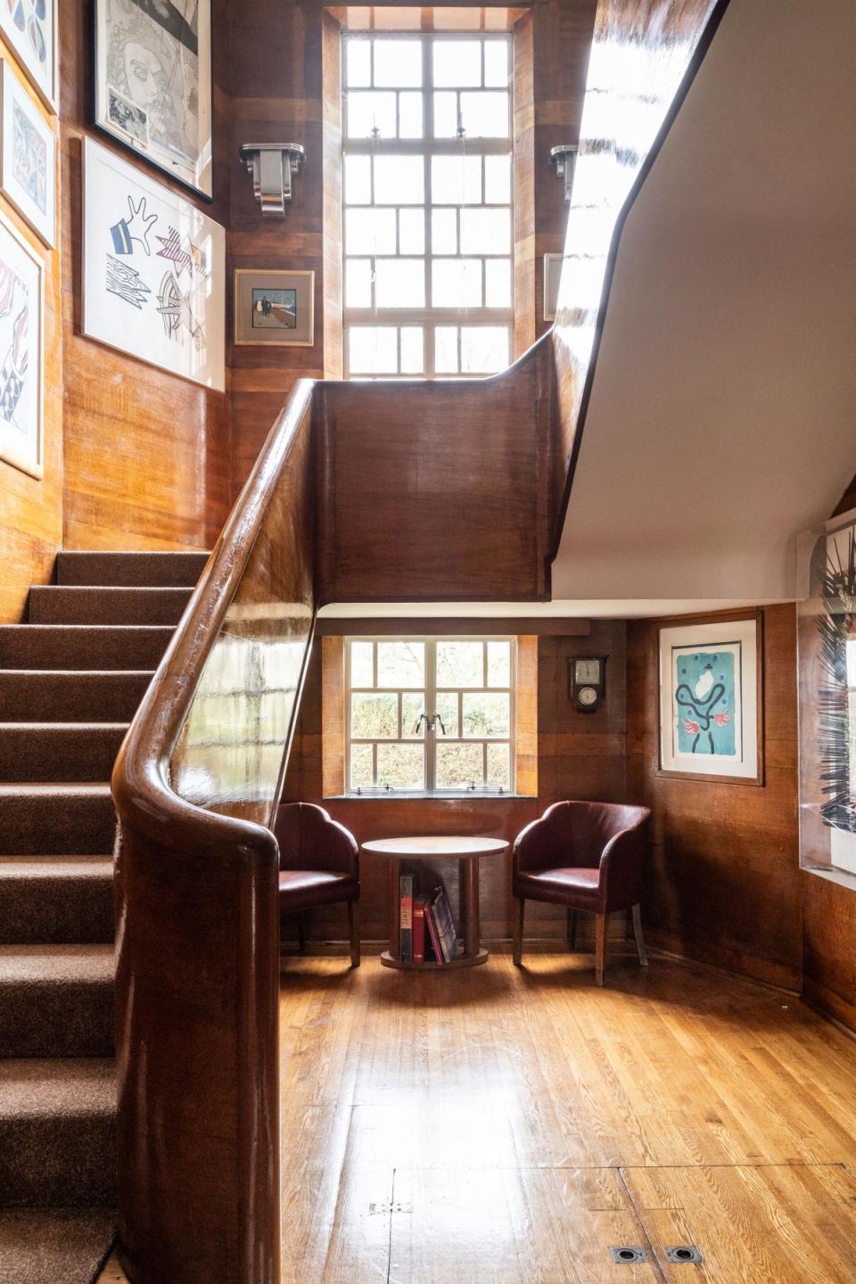 The stair hall is panelled with wood and features a wooden handrail (The Modern House)