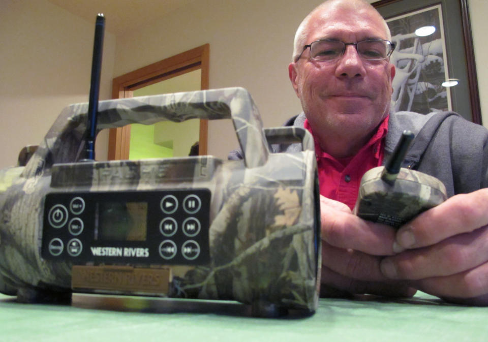 In this Oct. 12, 2012 photo, Mark Dahms, sitting in his Waukesha, Wis., home, works with the animal caller he plans to use to play the sound of a rabbit in distress to help attract wolves. The state's wolf hunt begins Monday, Oct. 15, and hundreds of hunters are headed to the woods of northern Wisconsin. (AP Photo/Carrie Antlfinger)